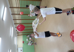 Uczniowie klasy trzeciej b ćwiczą z balonami i gazetami.